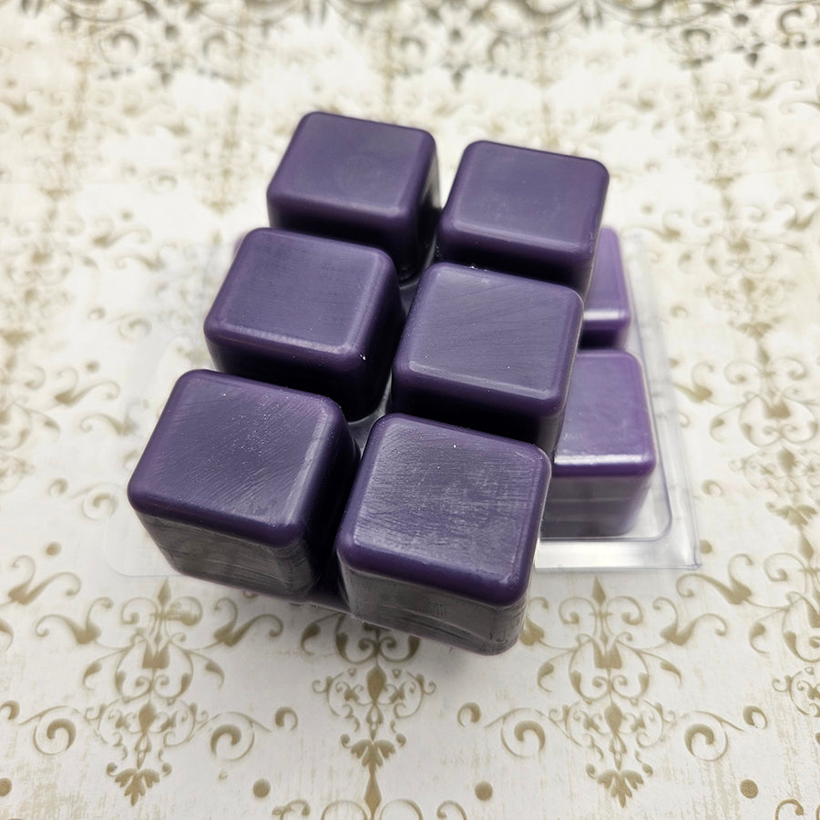 A set of wax melts in a clamshell on a white and gold patterned background. The pictured scent is Meteor: Soul of the Black Mage.