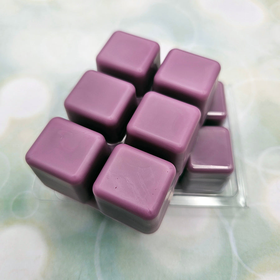 A set of wax melts out of a clamshell on light green background with white circles.  The pictured scent is Dance, Destined Weaveress: Aglaea.