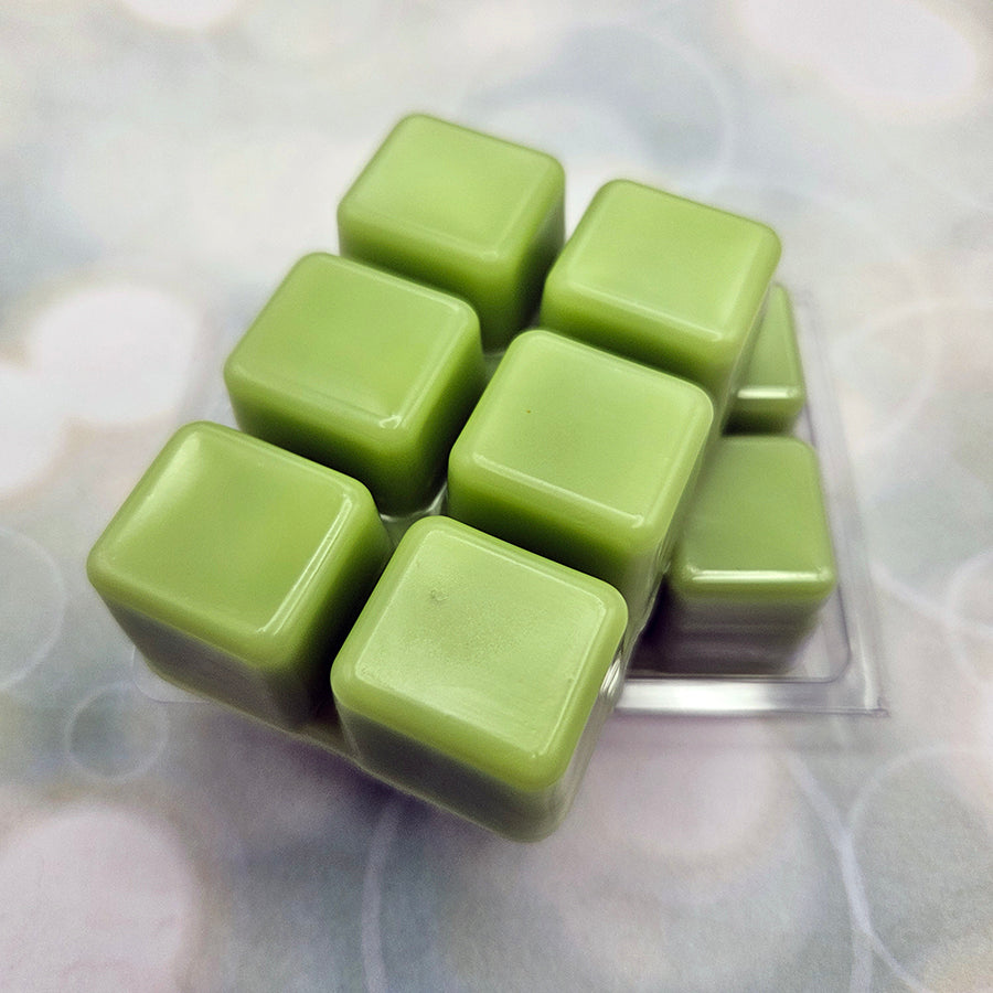 A set of wax melts out of a clamshell on light green background with white circles.  The pictured scent is Sprouting Life Sculpts Earth: Anaxa.