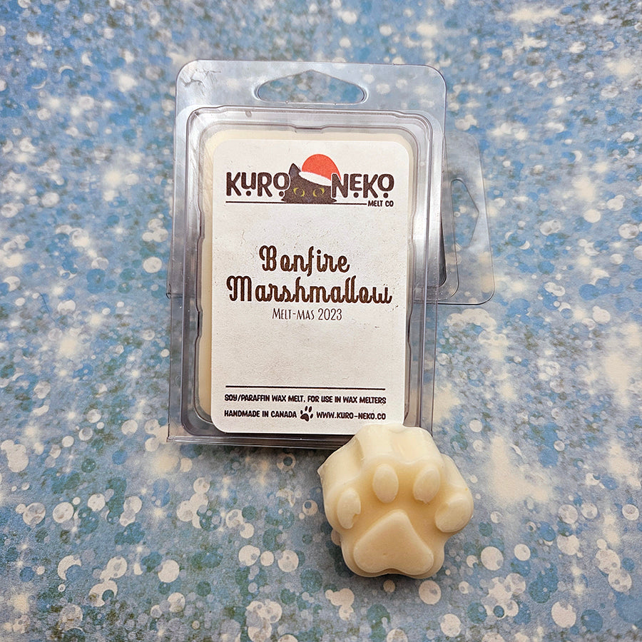 A set of wax melts in a clamshell on a blue speckled background with a paw shaped wax melt in front of it. The pictured scent is Bonfire Marshmallow.