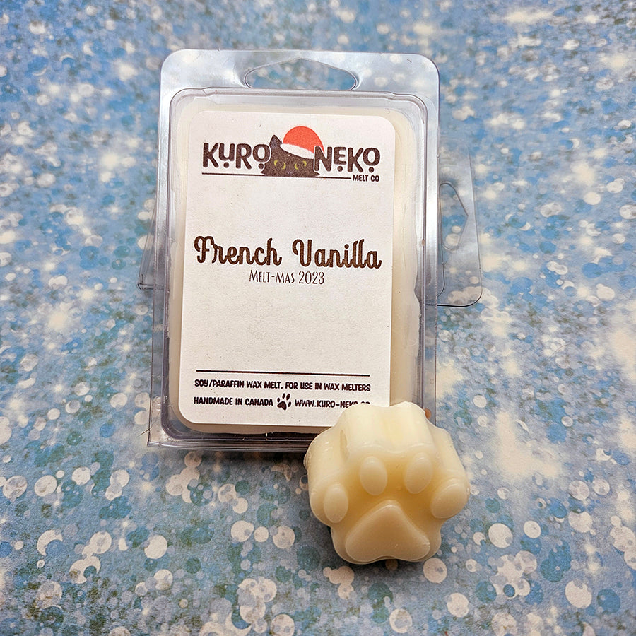 A set of wax melts in a clamshell on a blue speckled background with a paw shaped wax melt in front of it. The pictured scent is French Vanilla.