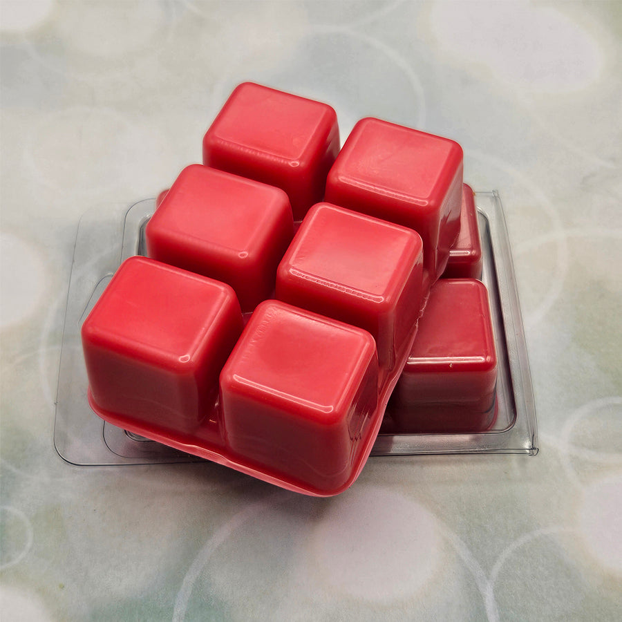 A set of wax melts out of a clamshell on a light green background with circles. The pictured scent is Nectar Blitz: Gallagher.