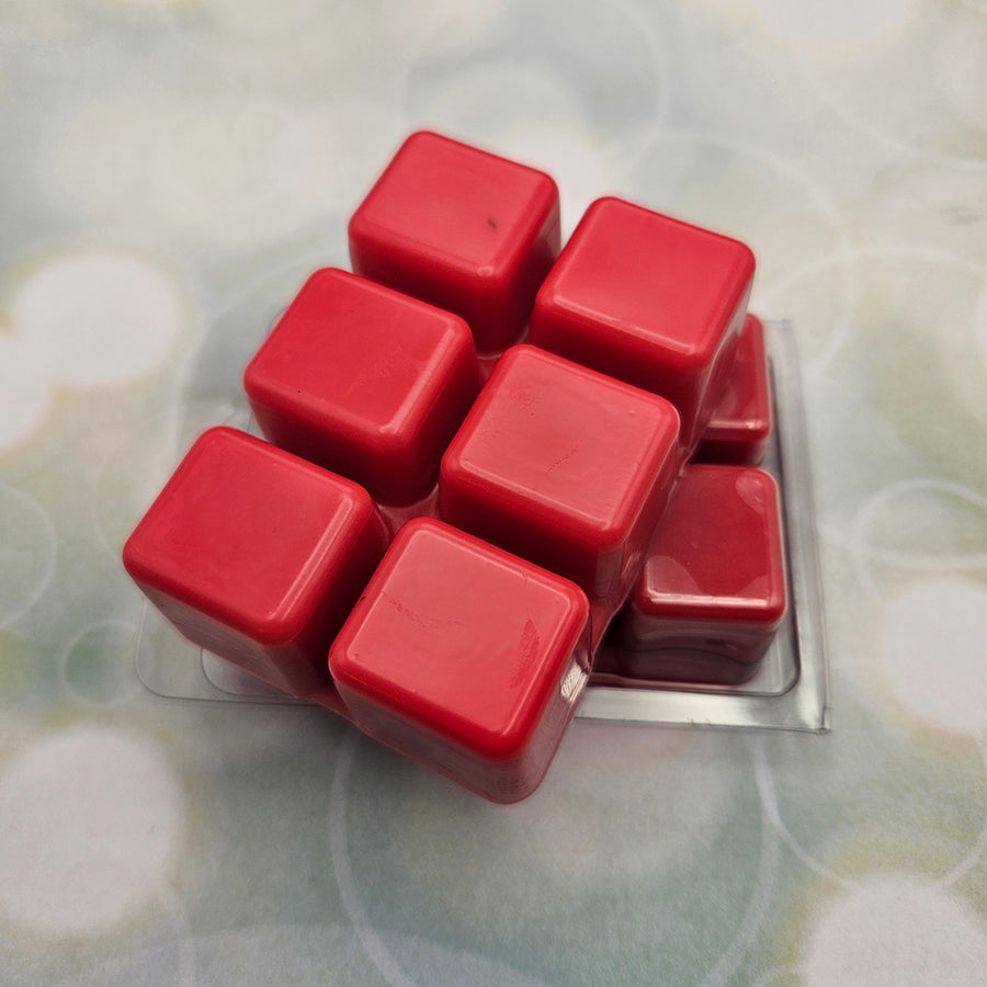 A set of wax melts in a clamshell on a light green background with circles. The pictured scent is Heavenly Flare: Himeko.