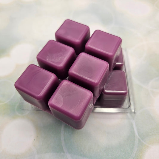 A set of wax melts in a clamshell on a light green background with circles. The pictured scent is Lightbringer: Jing Yuan.