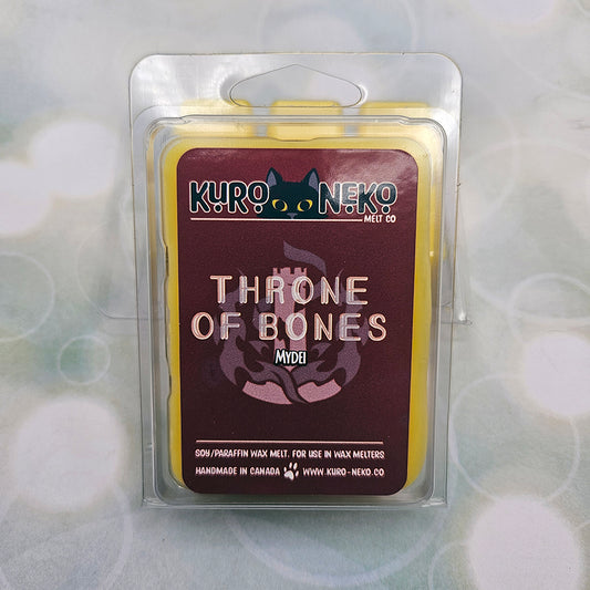 A set of wax melts in a clamshell on light green background with white circles. The pictured scent is Throne of Bones: Mydei.