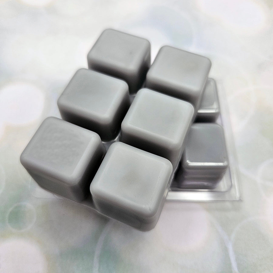 A set of wax melts out of a clamshell on light green background with white circles.  The pictured scent is He Who Bears the World Must Burn: Phainon.