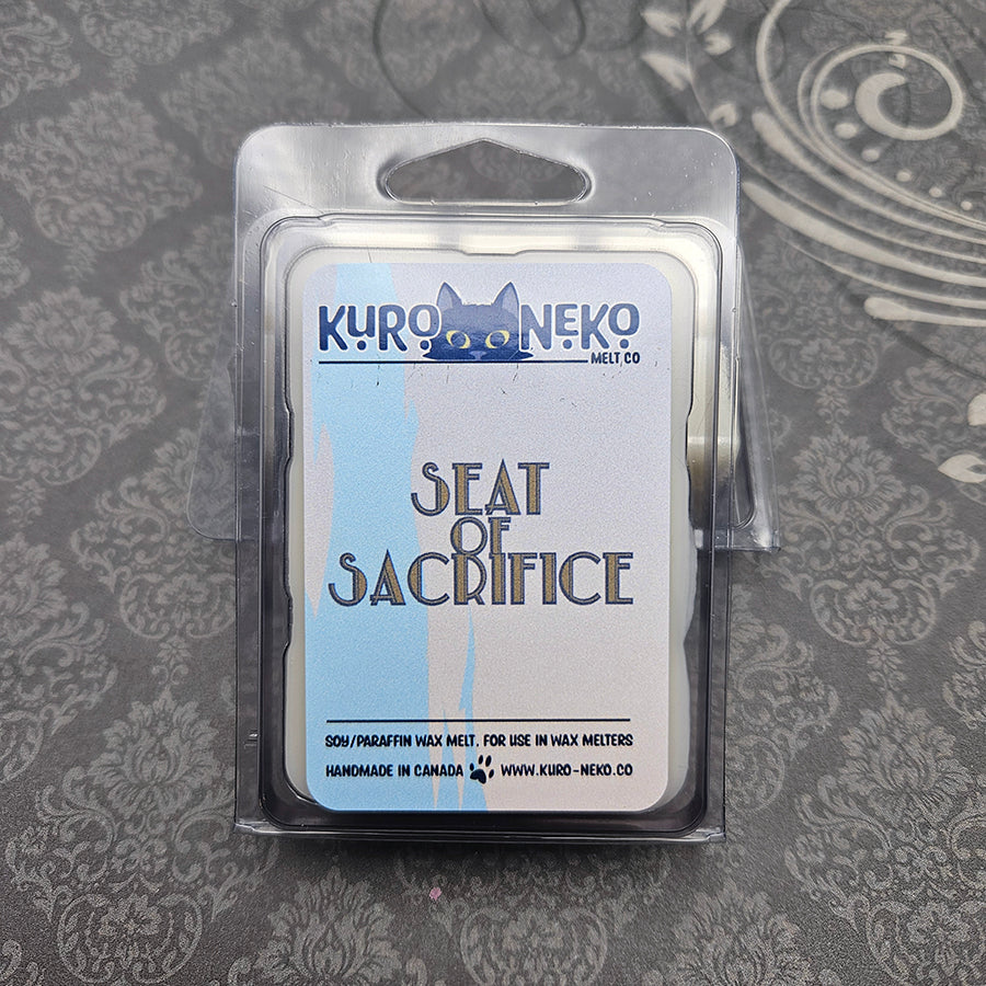 A set of wax melts in a clamshell on a dark grey patterned background. The pictured scent is Seat of Sacrifice: Warrior of Light.