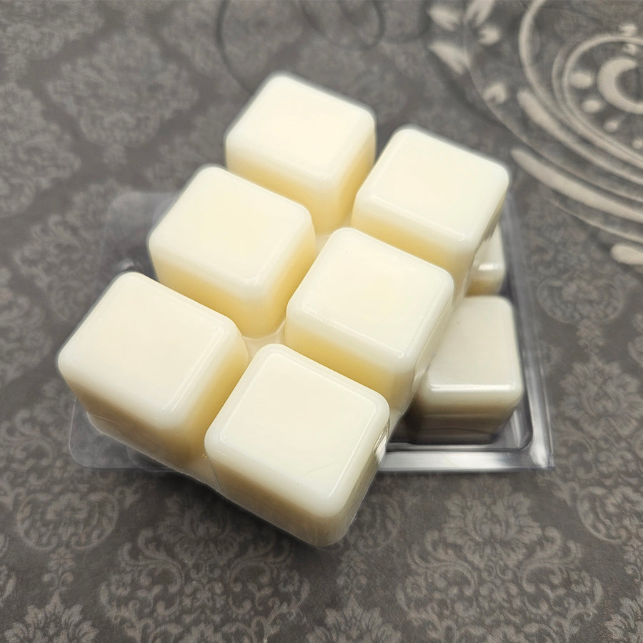 A set of wax melts in a clamshell on a dark grey patterned background. The pictured scent is Seat of Sacrifice: Warrior of Light.