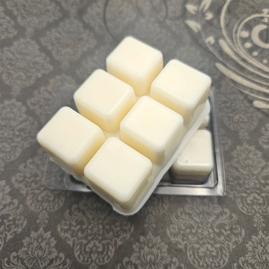 A set of wax melts in a clamshell on a dark grey patterned background. The pictured scent is The Ewer Brimeth: Sharlayan.