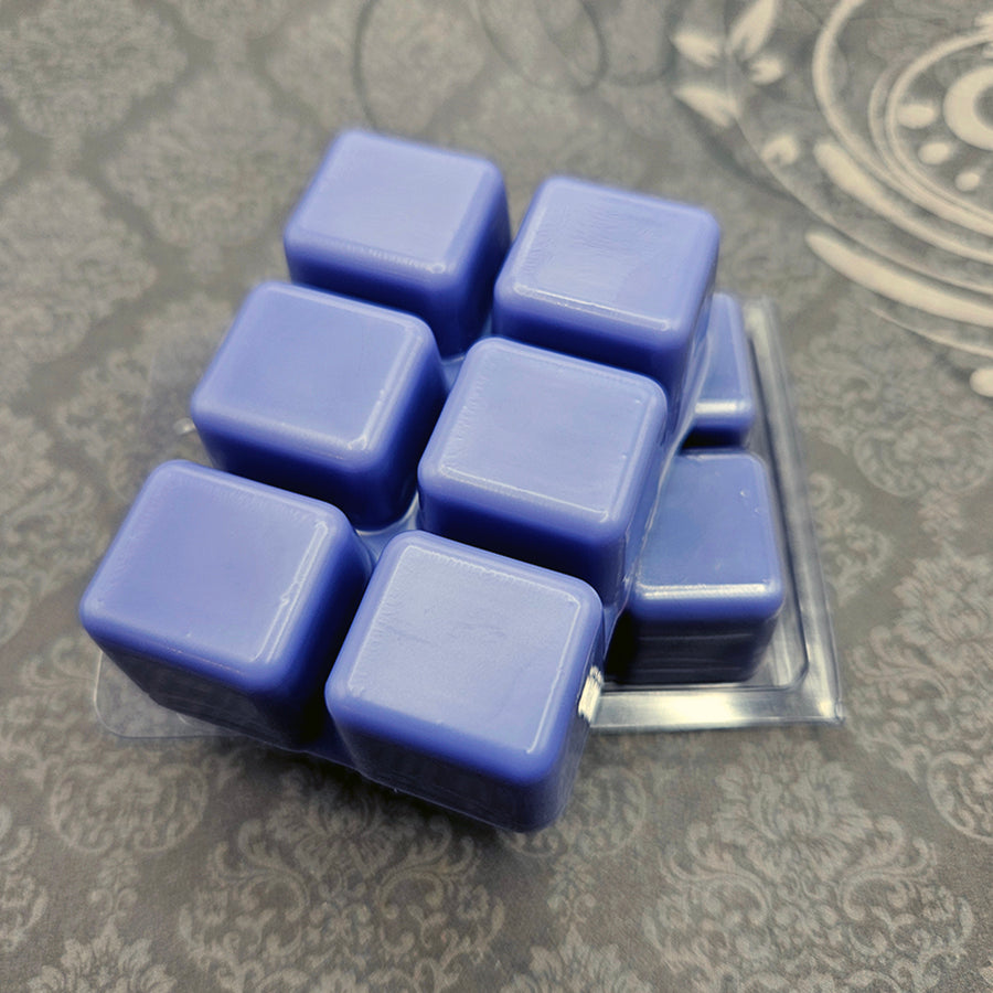 A set of wax melts in a clamshell on a dark grey patterned background. The pictured scent is Starless Skyline: Solution Nine.