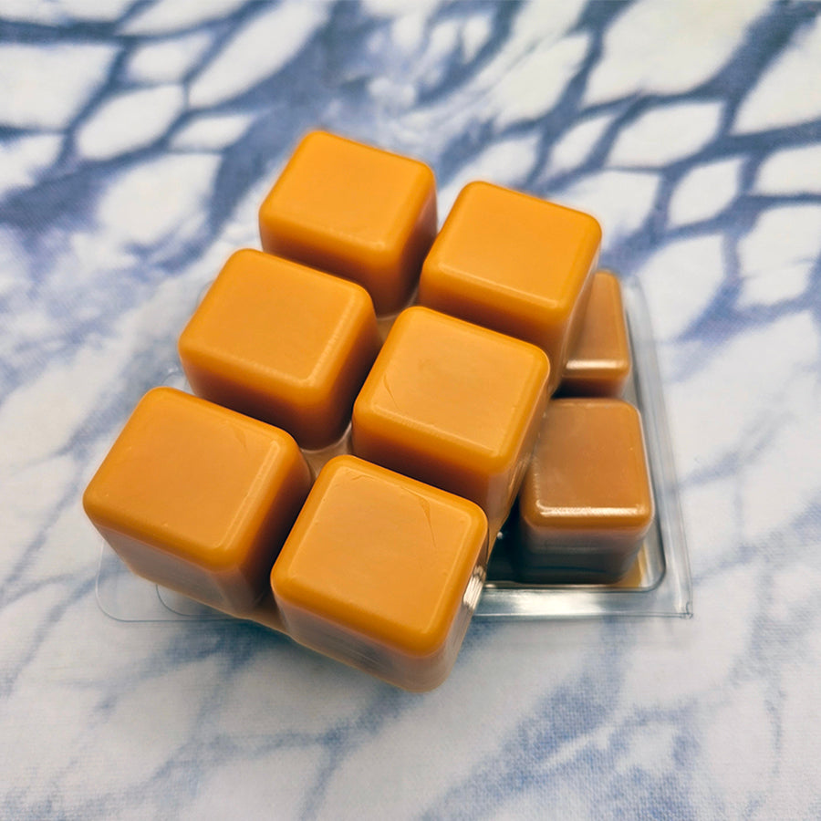 A set of wax melts in a clamshell on a dark blue and white tie dye background. The pictured scent is Dawn of Resolve: Wuk Lamat.