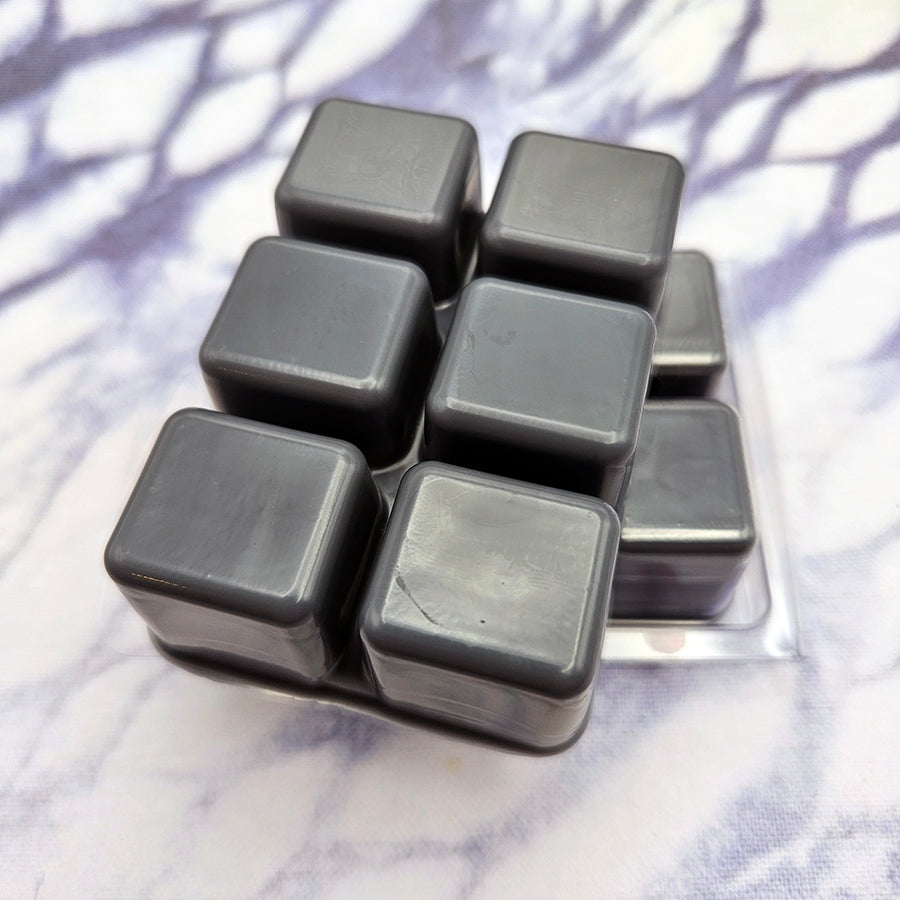 A set of wax melts in a clamshell on a pale grid background. The pictured scent is A New Beginning: Zero.